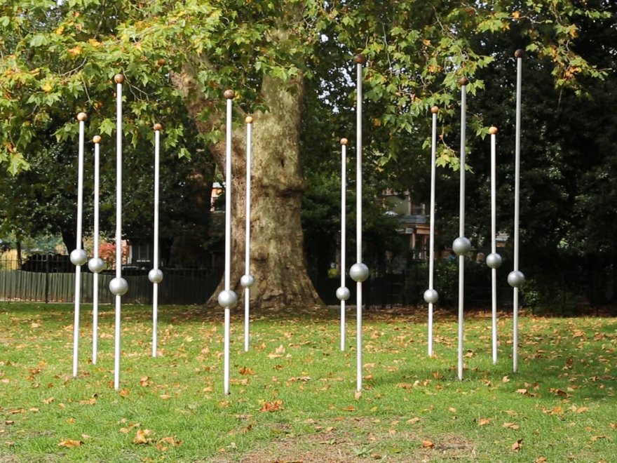 A sculpture with long sticks and balls in a park