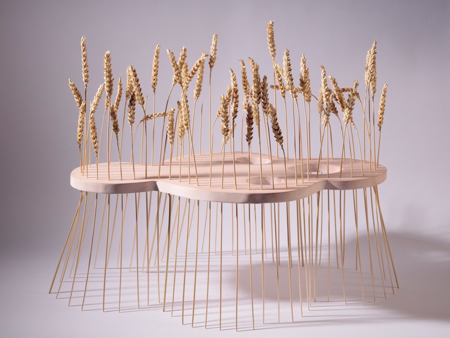 wooden sculpture with ears of corn sticking through it like legs holding it up