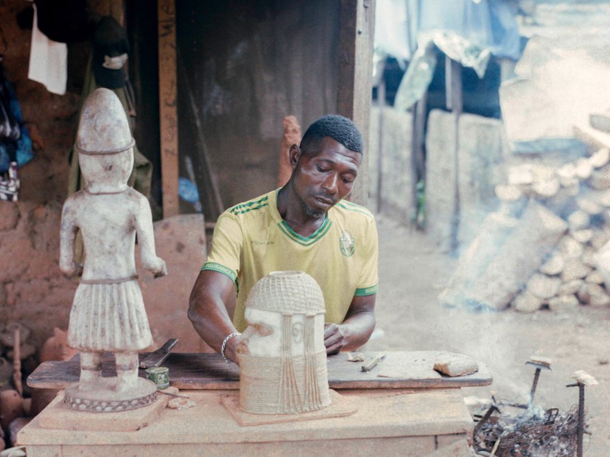 A man sits behind a table where he crafts
