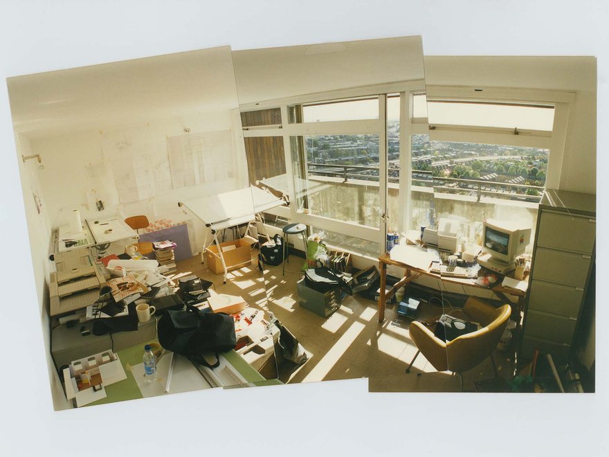 Interior shot of a sunny design studio with large glass windows overlooking a vista of London.