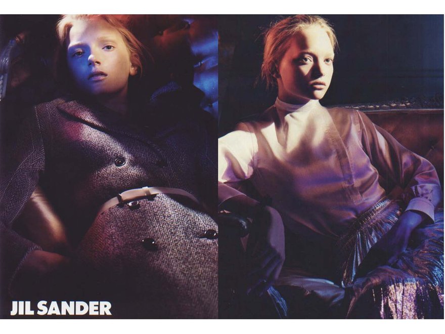 Split image of a fashion editorial showing a model reclining in minimalist Jil Sander-style clothing — on the left wearing a tailored textured coat with a belt, and on the right in a high-neck blouse and pleated skirt, lit with dramatic shadows.