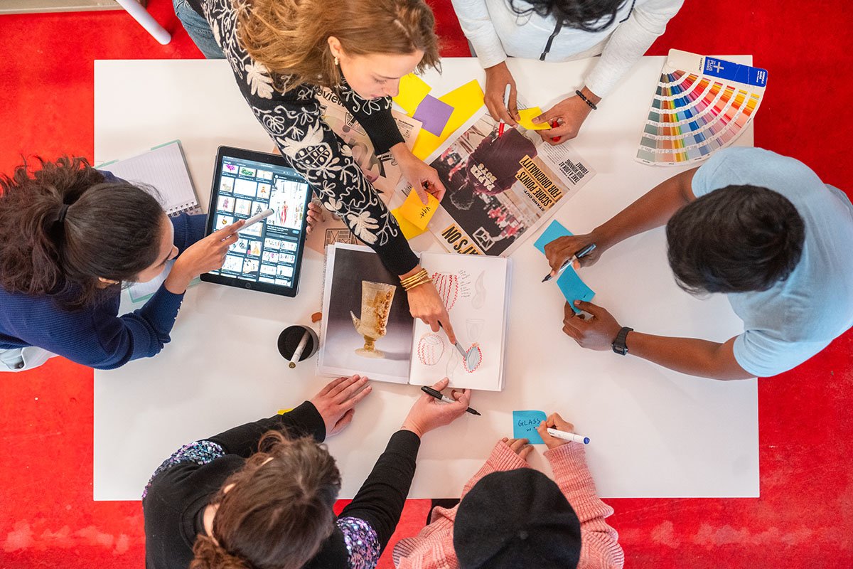 A group of RCA students collaborate on a creative project with pens and post it notes around a table