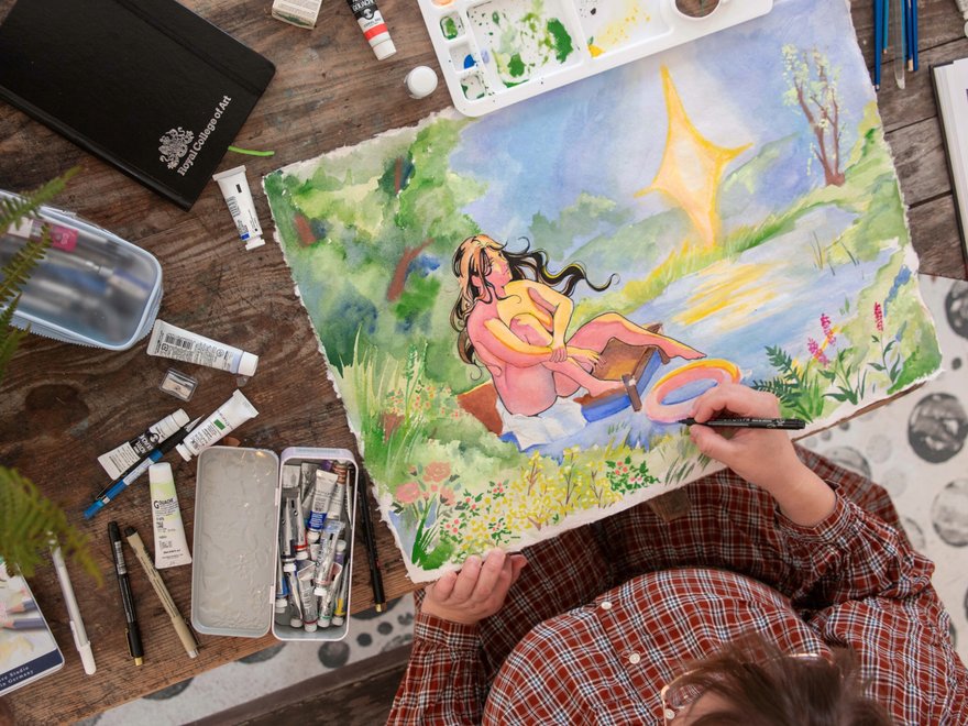 An artists table showing sketchbooks and paintings