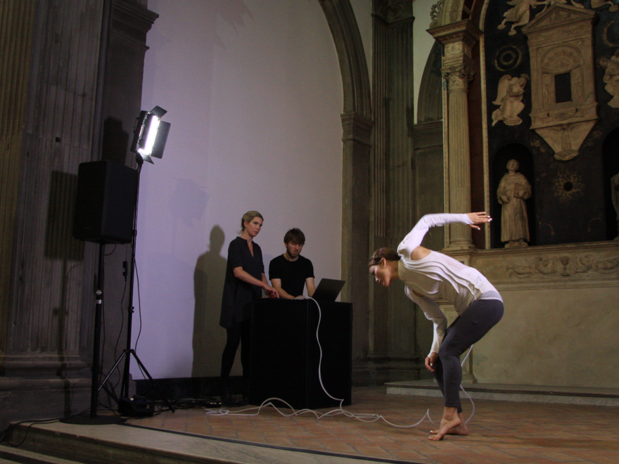 A woman performs contemporary dance on stage wearing white