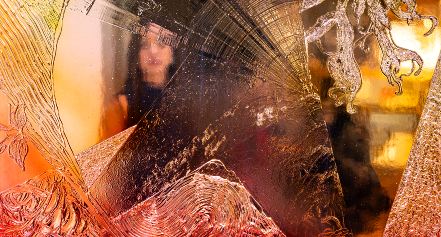 A shimmering feflective artwork with different colours and a woman's reflection